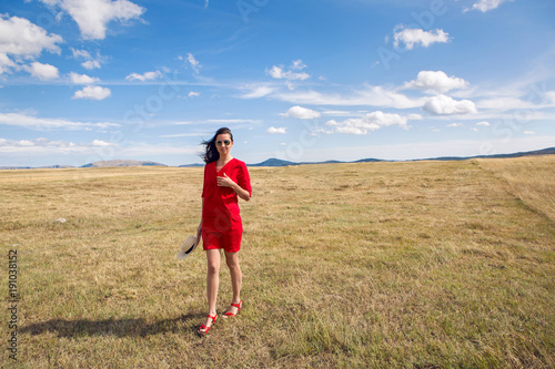 sexy girl in red dress standing in a field in autumn