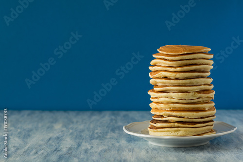 Stack of pancakes with honey on blue background