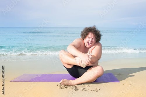 Fitness at the sea. Funny fat guy and yoga. 