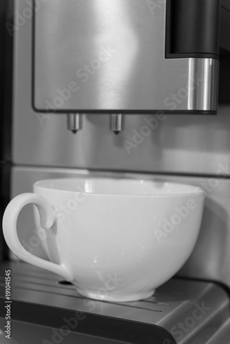 White cup and coffee machine in black and white close up
