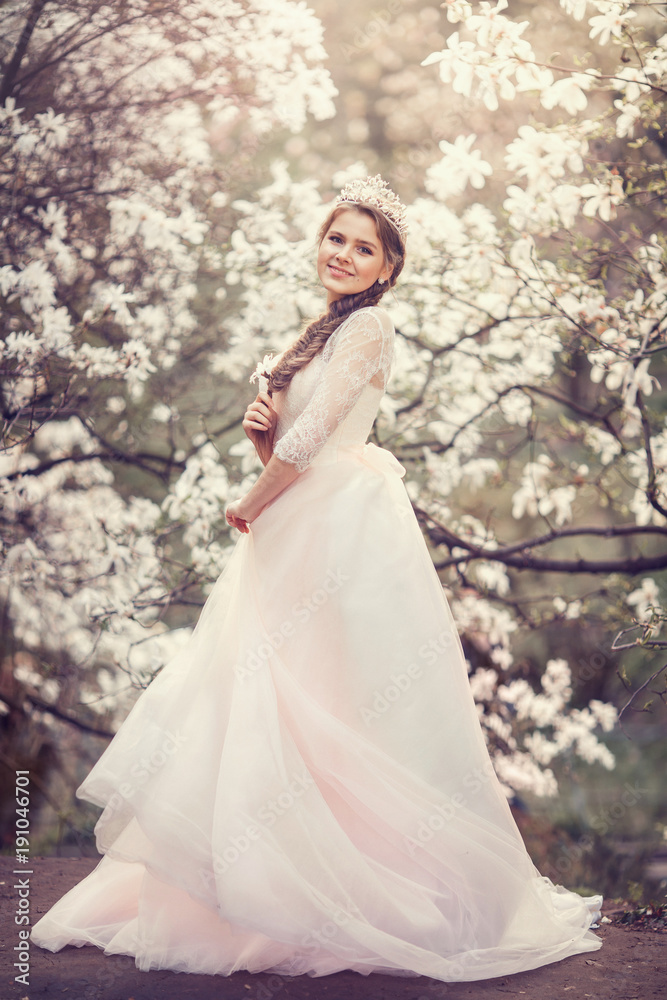 Beautiful young woman with crown in blossom magnolia garden. Spring. Beautiful young woman with crown in blossom magnolia garden. Spring.