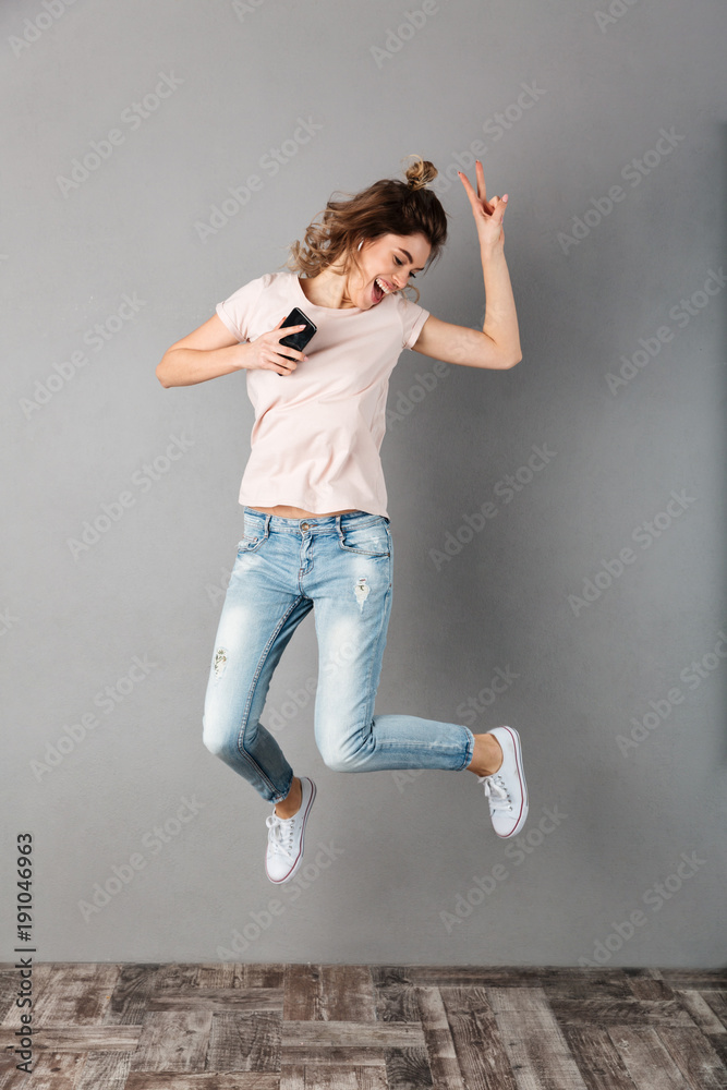 Full length image of Joyful woman in t-shirt listening music