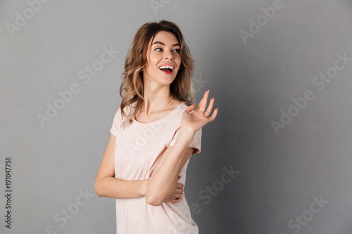 Image of Surprised happy woman in t-shirt waving