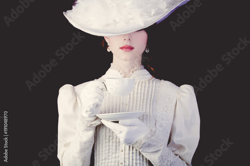 woman in white Victorian era clothes with cup of tea