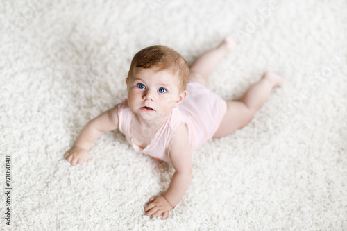 Little funny baby girl lifting body and learning to crawl.