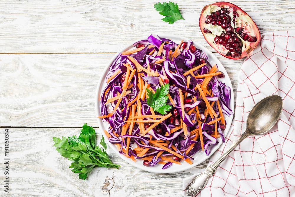 Red cabbage coleslaw with carrot pomegranate on white wooden background. Top view, copy space. 
