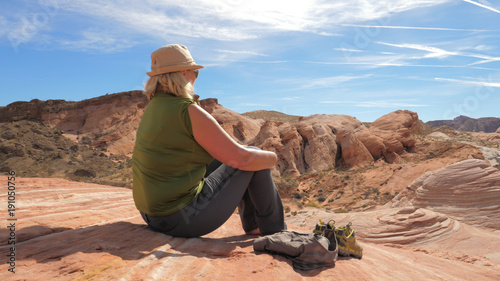 Active Woman Tourist Sitting Resting On Red Rock And Admiring Views Of Canyon