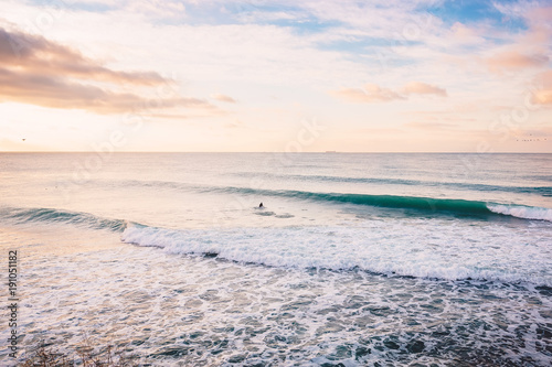 Surfer ride on perfect wave in ocean. Landscape with waves and sunrise colors