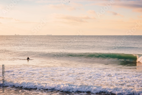 Surfer and perfect breaking barrel wave. Landscape with sunrise colors