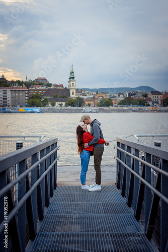 Photography The charming couple in love is tenderly rubbing noses on the iron pier near River Danube in Budapest, Hungary during the sunset