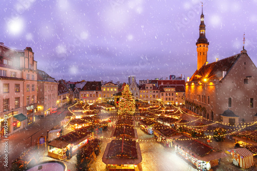 Decorated and illuminated Christmas tree and Christmas Market at Town Hall Square or Raekoja plats at snowy winter night, Tallinn, Estonia. Aerial view