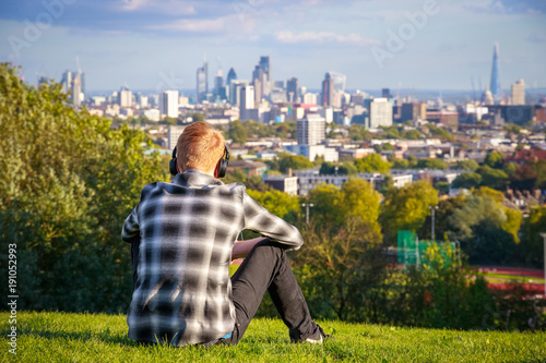 Back view of a tourist looking over London city skyline from Parliament Hill in Hampstead Heath