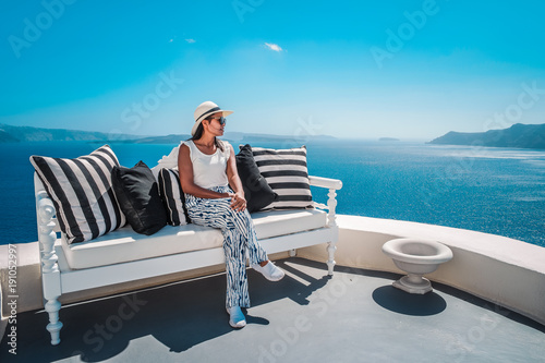 young woman on vacation at Santorini Greece looking out over the blue ocean with olg whitewashed buildings and a white blue greek church photo