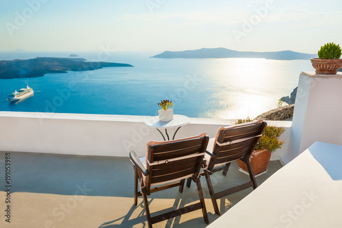 Two chairs on the terrace with sea views. Santorini island, Greece at sunset