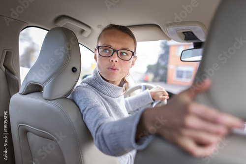 Fotografija Pretty, young woman driving her new car -going in reverse, being quite stressed