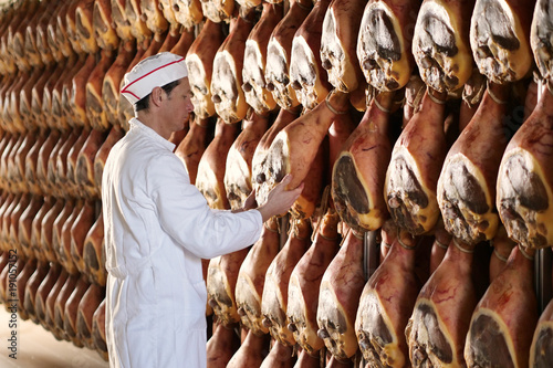 Photography In a ham factory, a man in charge of quality control walks between the hams and controls, the perfume and the certified Italian quality