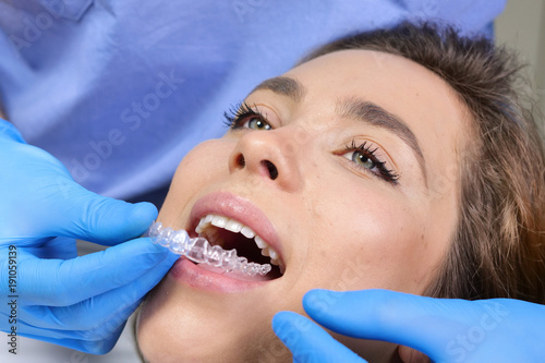 In a professional practice, a dentist checks the dentition of the patient, and she is happy with the visit, smiling, showing the perfect white teeth. Concept of: dentists, healthcare, perfect smile.