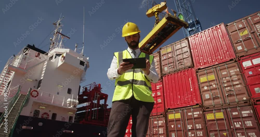 A young manager doing inspection rounds through an industrial harbor working on a digital tablet. Shot on RED Epic.