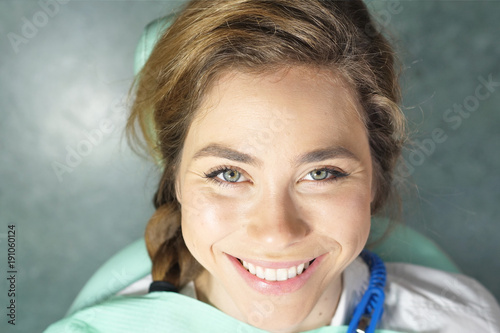 In a professional practice, a dentist checks the dentition of the patient, and she is happy with the visit, smiling, showing the perfect white teeth. Concept of: dentists, healthcare, perfect smile.