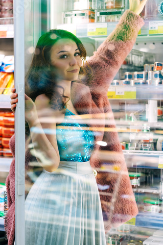 Woman choosing product form refrigerator in supermarket