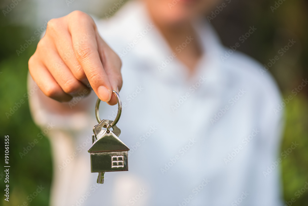 house key in woman hand and green leaves background - obrazy, fototapety, plakaty 