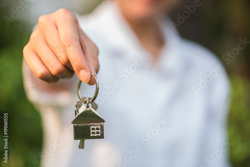 house key in woman hand and green leaves background