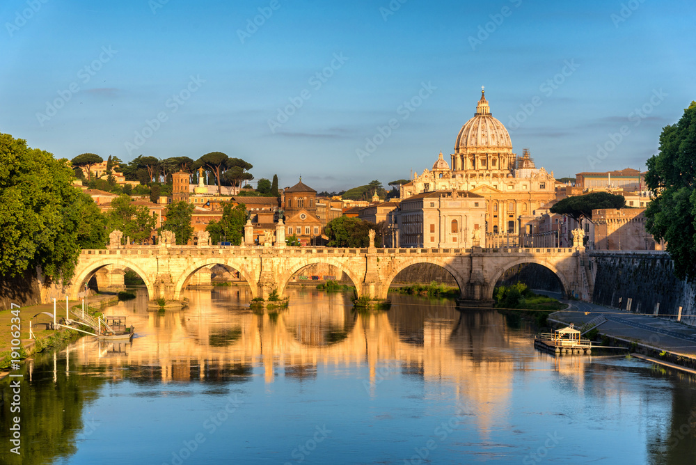 Sunrise landscape view in early morning of St. Peters Basilica in the Vatican and the Ponte Sant'Angelo, Bridge of Angels, at the Castel Sant'Angelo and river Tiber in Rome, Italy
