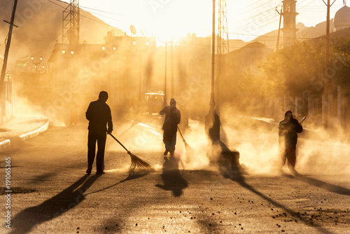 Road sweeper worker cleaning leh city market street with broom tool in early morning photo