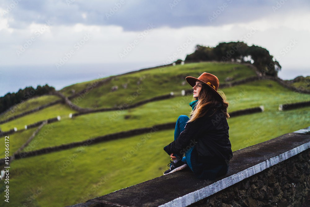 Woman sitting on fence at field Woman sitting on fence at field