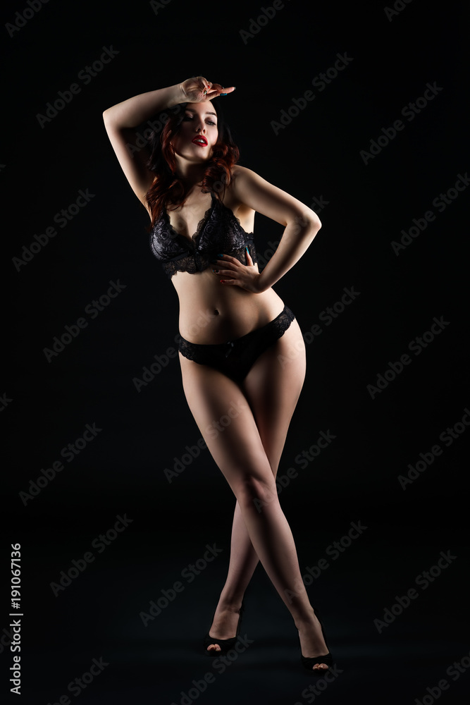 Beautiful sexy woman in lingerie posing on black studio background, low key studio shot