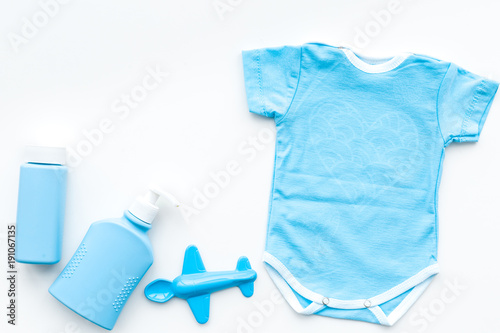 Blue baby clothes for little boy. Bodysuit  toys  cosmetics on white background top view copy space