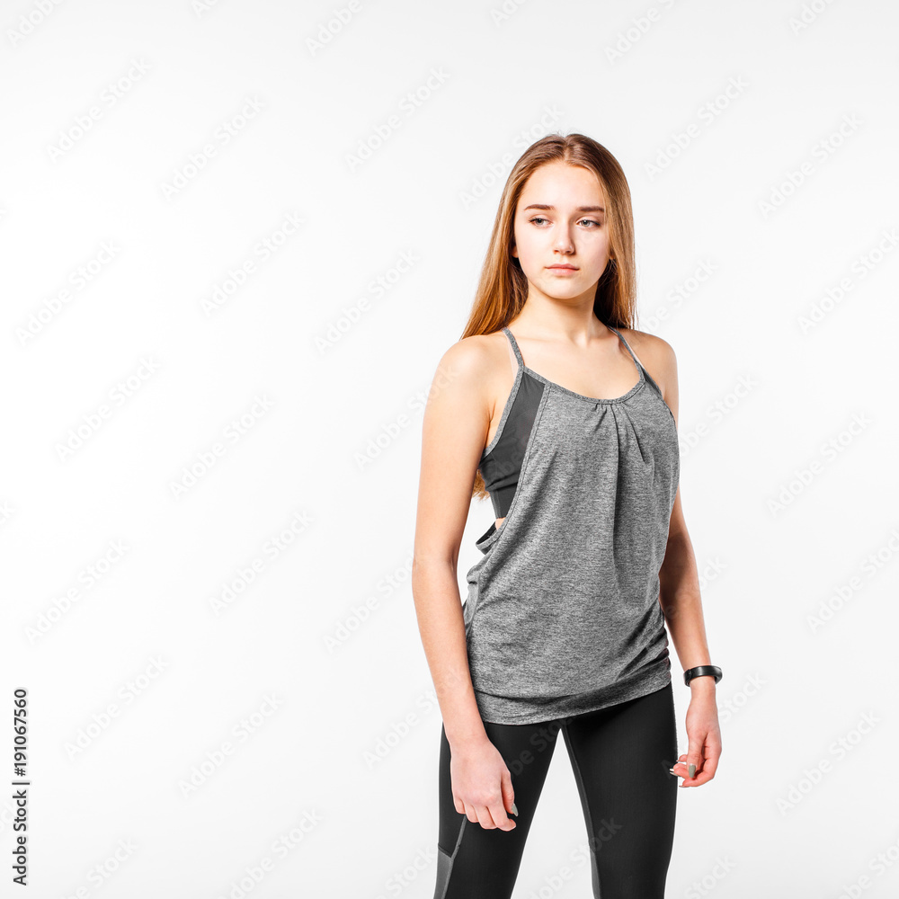 Young confident teenage fitness girl standing against white background Young confident teenage fitness girl standing against white background