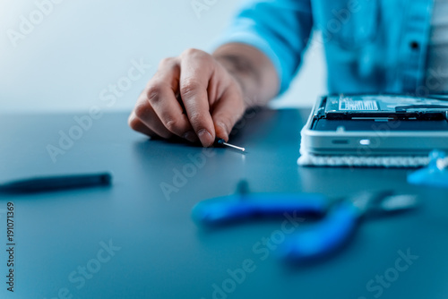 Laptop repair concept. Close-up of male hands holding screwdriver.