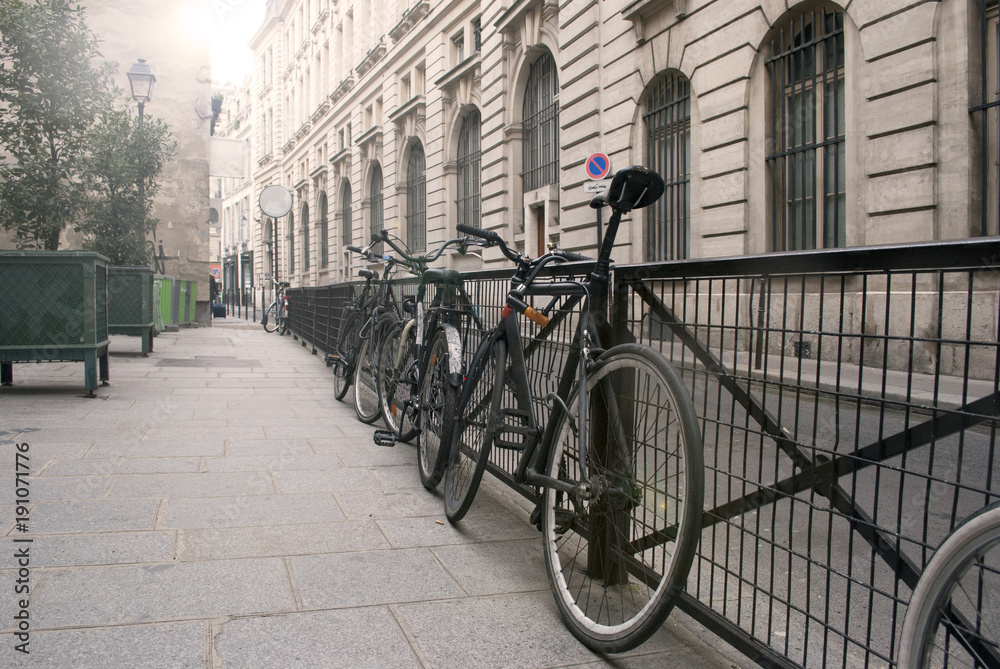 Bicycles next to metal fence on the street in an old city; cityscape background.