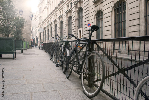 Bicycles next to metal fence on the street in an old city; cityscape background.