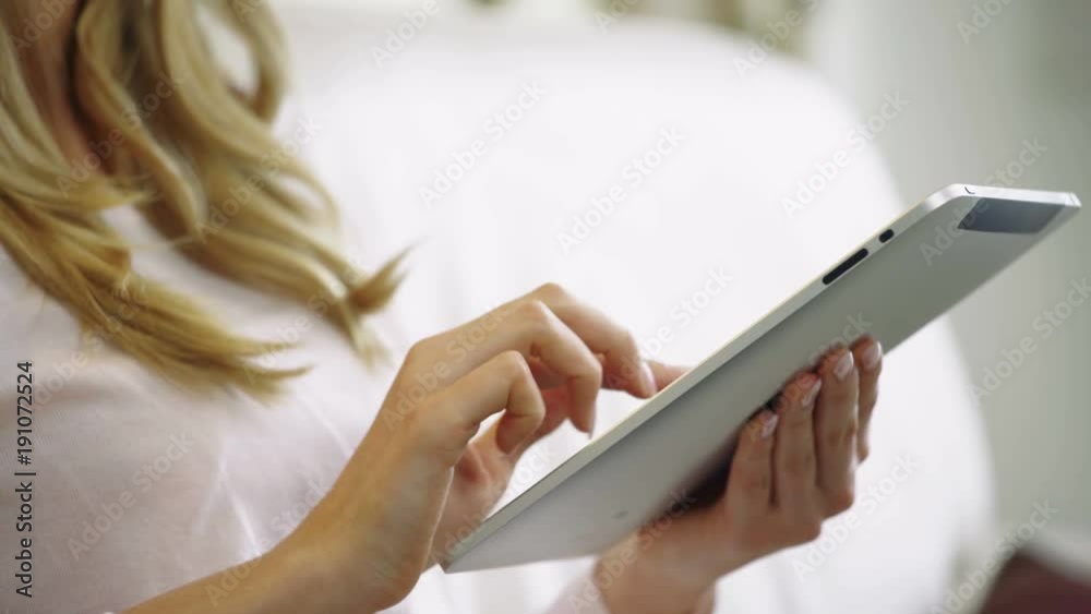 Young blonde woman searching with tablet on couch 