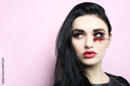 Beautiful girl, brunette with beautiful make-up in and lengthened eyelashes on a pink background. © Studio KIVI