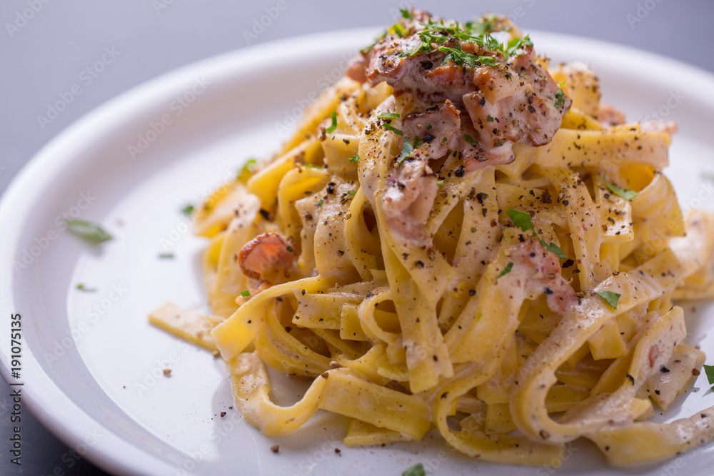 close up of pasta carbonara, on a white plate with background close up of pasta carbonara, on a white plate with background
