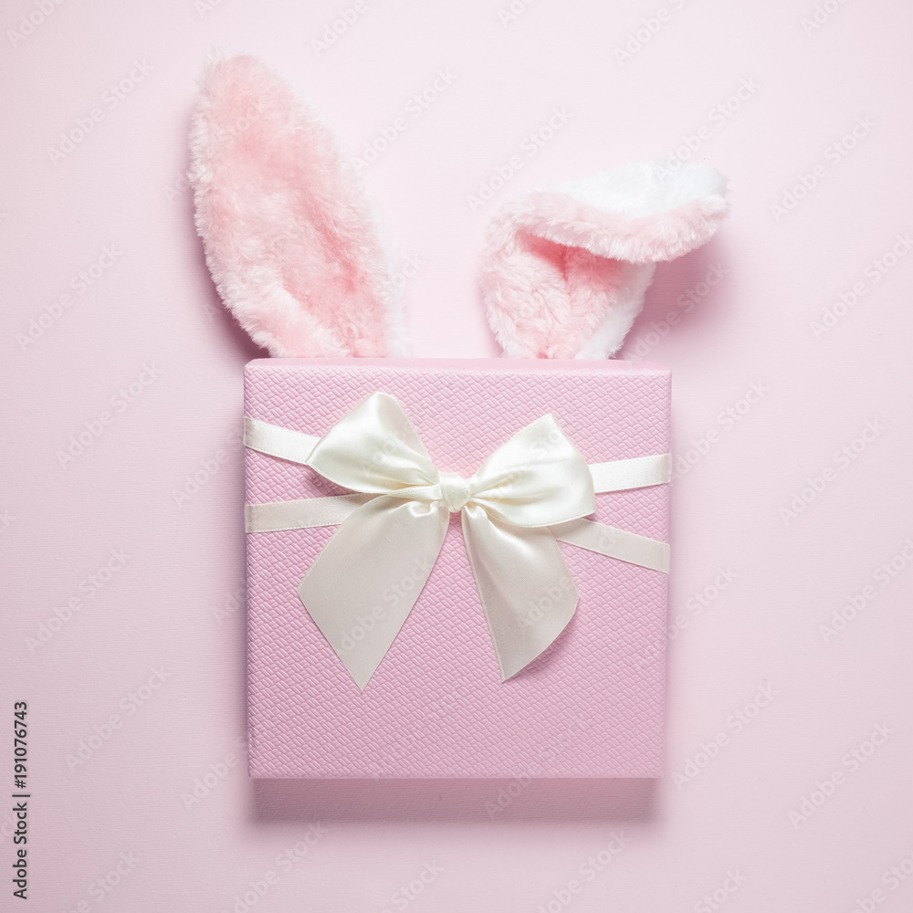 Bunny ears and present on plain pink background Bunny ears and present on plain pink background