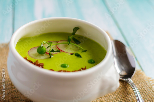 Cream of green peas soup in a white bowl on a napkin