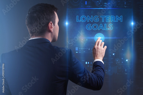 Business, Technology, Internet and network concept. Young businessman working on a virtual screen of the future and sees the inscription: Long term goals