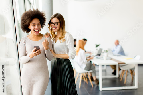 Pretty young women with moble phone in the office photo
