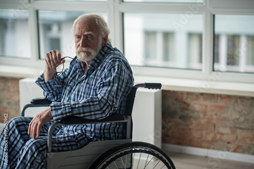 Fotografija Sorrowful old man holding his eyeglasses with vacant look
