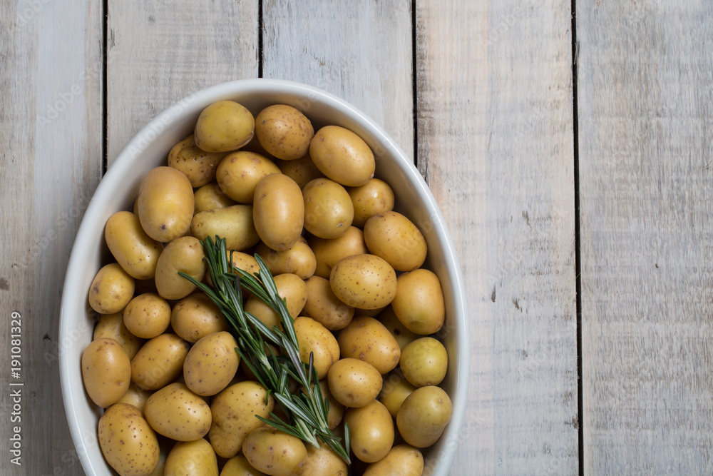 Raw baby potatoes in pan with rosemary, ready to cook in oven Raw baby potatoes in pan with rosemary, ready to cook in oven