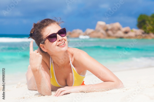 portrait of long haired woman in bikini and sunglasses lying on tropical beach. La Digue  Seychelles