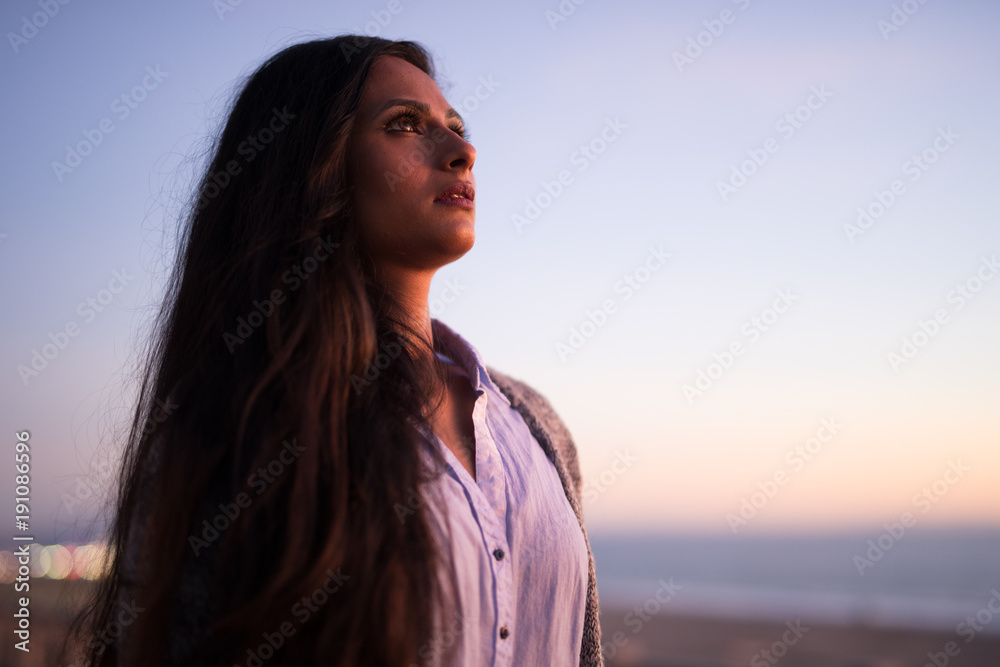 Young Indian woman looking up sunset sky 