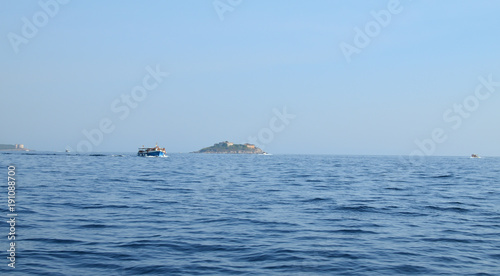 Tourist boat sailing on a sea passing an island on its way