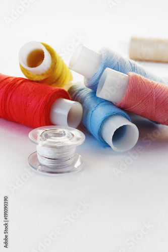 Multicolored threads, scissors, buttons, fabric and various sewing accessories on a white background with copy space flat lay