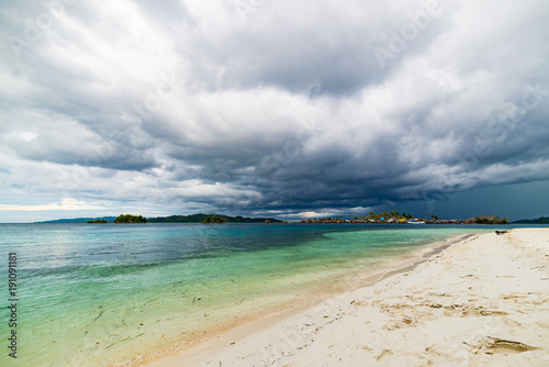 Tropical beach, caribbean sea, transparent turquoise water, remote Togean Islands (Togian Islands), Sulawesi, Indonesia. Dramatic sky at sunset.