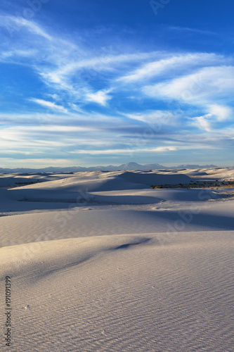 White sand dunes under wispy clouds in the evening